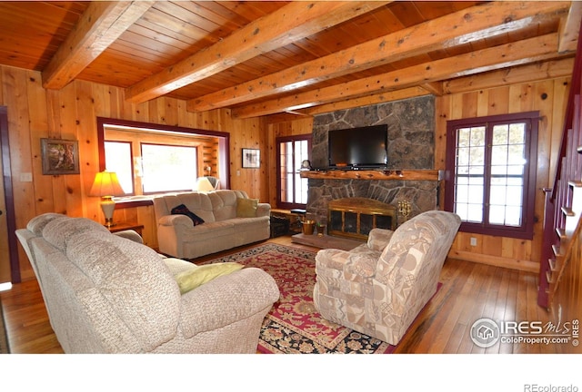 living room with beamed ceiling, hardwood / wood-style flooring, wooden walls, wooden ceiling, and a fireplace