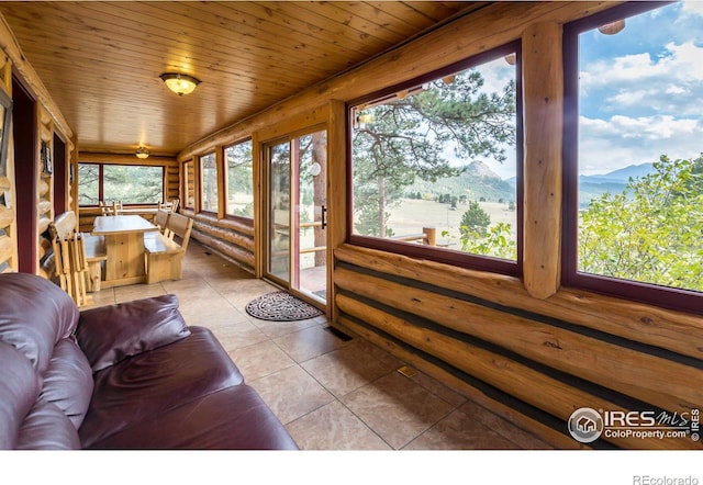 sunroom / solarium featuring wooden ceiling and a mountain view