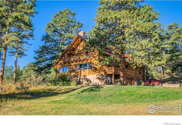 view of front of property with a deck, log exterior, a chimney, and a front yard