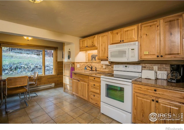 kitchen with white appliances, a wainscoted wall, light tile patterned flooring, a sink, and backsplash