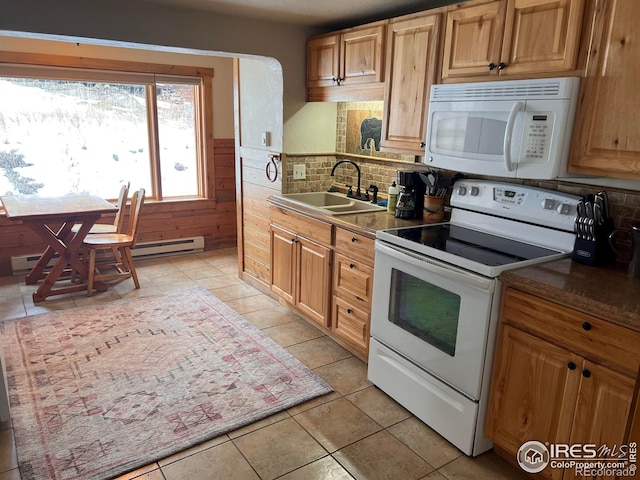 kitchen featuring tasteful backsplash, a wainscoted wall, light tile patterned floors, white appliances, and a sink