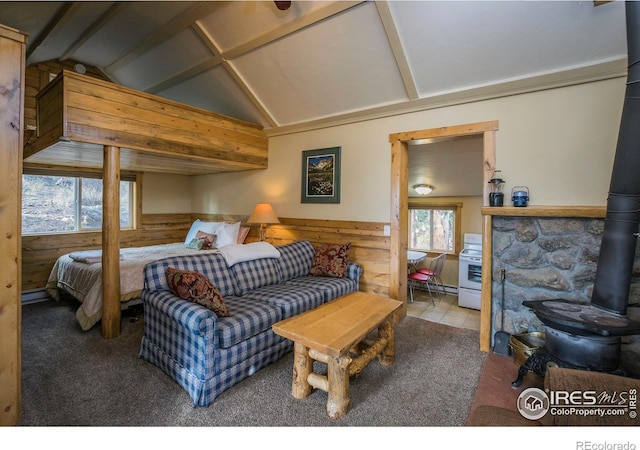 bedroom featuring lofted ceiling with beams, a wood stove, a wainscoted wall, and wood walls