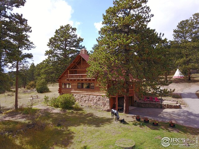 3501 Devils Gulch Rd, Estes Park, CO 80517 - view of front of property featuring a chimney, an attached garage, stone siding, log exterior, and a front lawn