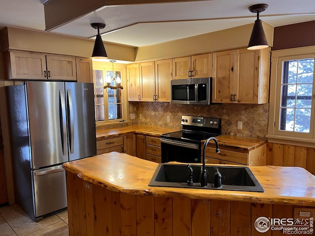 3501 Devils Gulch Rd, Estes Park, CO 80517 - kitchen featuring appliances with stainless steel finishes, butcher block countertops, decorative backsplash, hanging light fixtures, and light tile patterned flooring