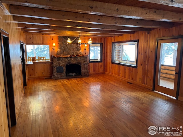 3501 Devils Gulch Rd, Estes Park, CO 80517 - unfurnished living room with beamed ceiling, hardwood / wood-style flooring, a stone fireplace, and wooden walls
