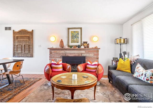 living area featuring visible vents, baseboards, wood finished floors, and a fireplace