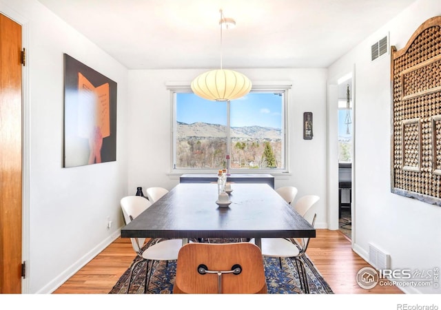 dining space featuring visible vents, baseboards, and light wood finished floors