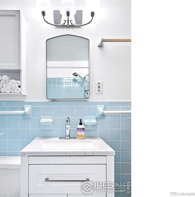 bathroom with toilet, tile walls, wainscoting, a chandelier, and vanity