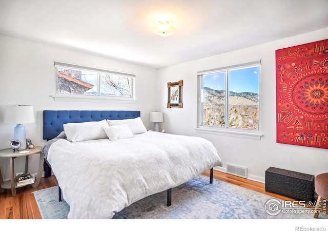 bedroom with wood finished floors, visible vents, and baseboards