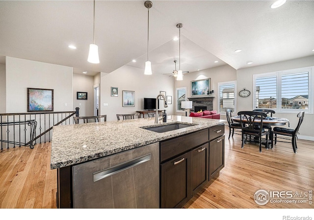 kitchen with a sink, decorative light fixtures, open floor plan, light wood-style floors, and a fireplace