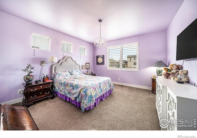 carpeted bedroom featuring a textured ceiling, baseboards, and an inviting chandelier