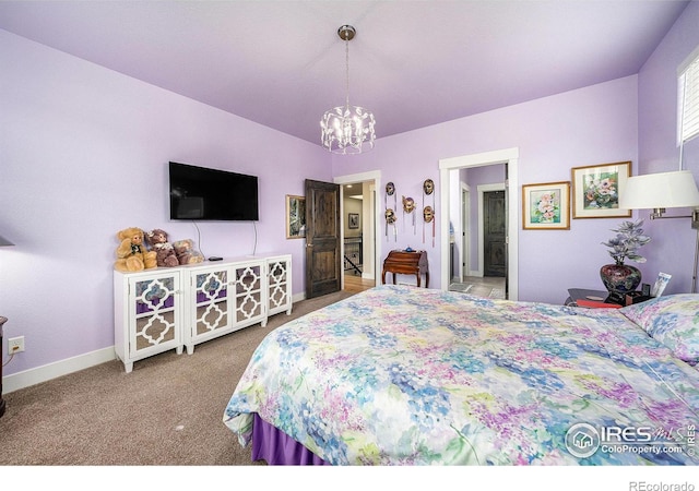 bedroom featuring carpet flooring, baseboards, ensuite bathroom, and a chandelier