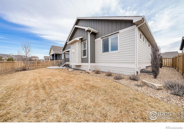 exterior space featuring board and batten siding, a fenced backyard, and a front yard