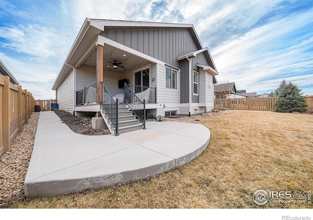 view of front of property with a front lawn, a ceiling fan, a fenced backyard, board and batten siding, and a patio area