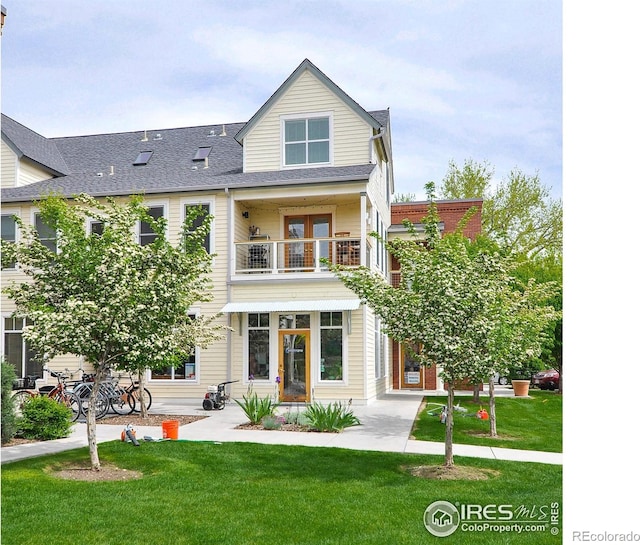 back of property featuring a yard, a shingled roof, and a balcony
