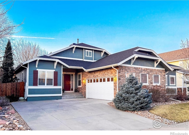 view of front of home featuring fence, concrete driveway, roof with shingles, a garage, and stone siding