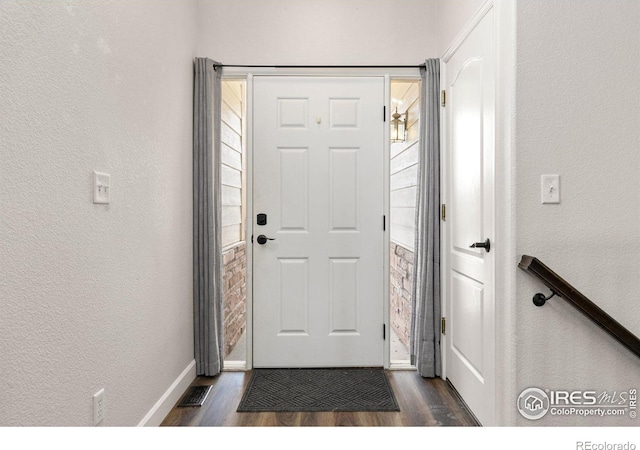 entryway with dark wood-style floors, visible vents, a textured wall, and baseboards