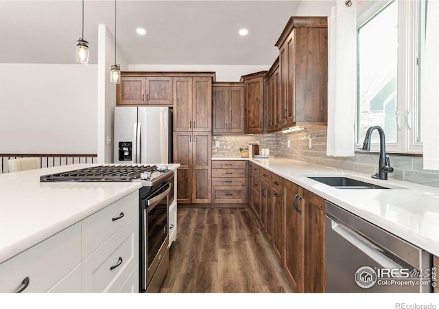 kitchen with a sink, tasteful backsplash, dark wood-style floors, stainless steel appliances, and light countertops