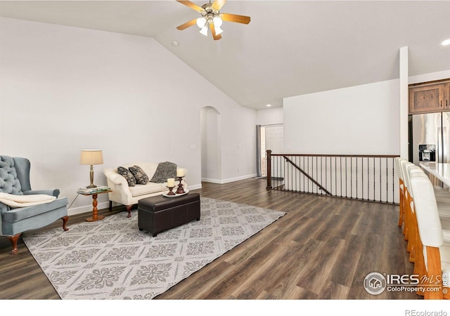 living area with baseboards, dark wood finished floors, an upstairs landing, arched walkways, and a ceiling fan