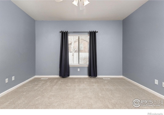 carpeted spare room featuring baseboards and ceiling fan