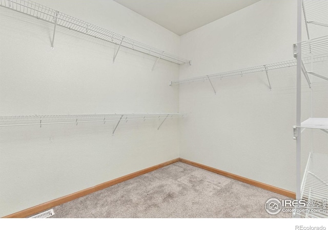 walk in closet with visible vents and light colored carpet