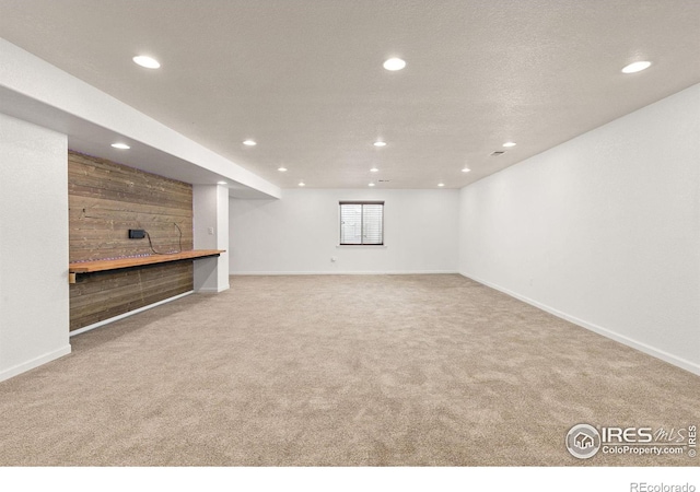 below grade area featuring recessed lighting, baseboards, carpet floors, and wooden walls