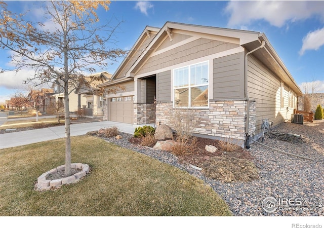view of front of house with central AC unit, driveway, a front lawn, a garage, and stone siding