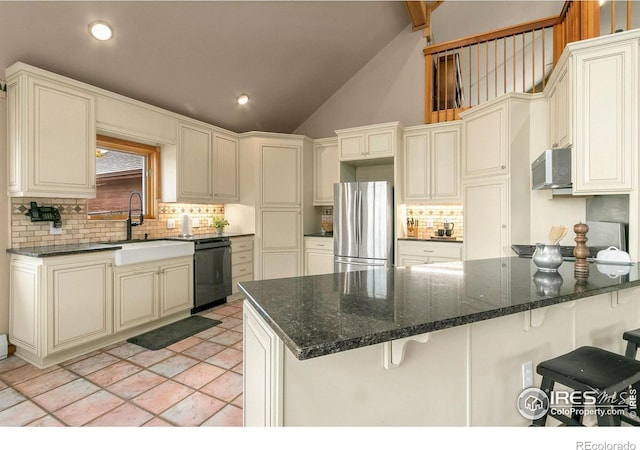 kitchen featuring a peninsula, freestanding refrigerator, a sink, black dishwasher, and a kitchen bar