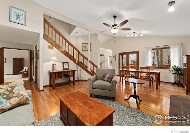 living room featuring lofted ceiling, stairway, light wood-style floors, and ceiling fan