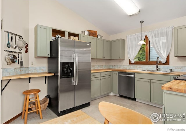 kitchen with green cabinetry, butcher block countertops, stainless steel appliances, and a sink