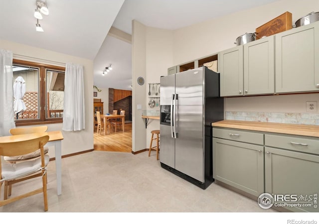 kitchen featuring vaulted ceiling, stainless steel fridge with ice dispenser, and baseboards