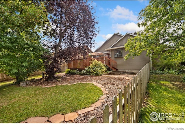 view of yard with a wooden deck, stairs, and fence