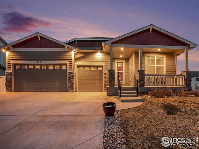 craftsman house with stone siding, a porch, concrete driveway, and an attached garage