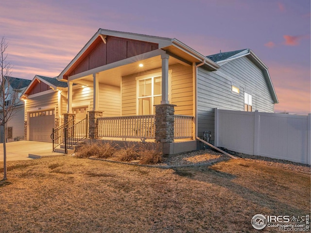 craftsman-style home featuring board and batten siding, fence, concrete driveway, covered porch, and an attached garage