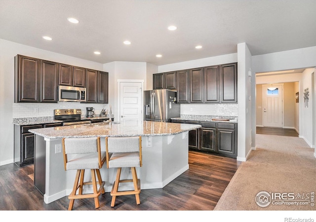 kitchen with a sink, dark brown cabinetry, an island with sink, and stainless steel appliances