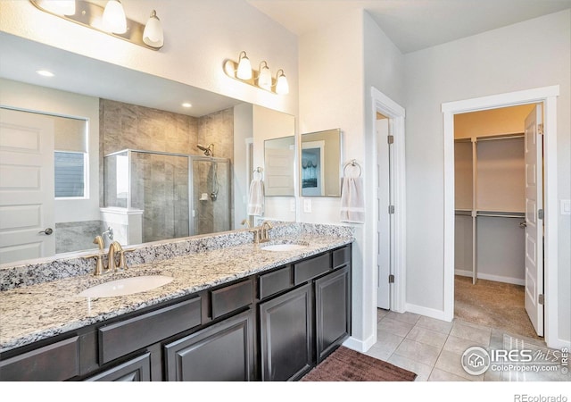 full bath with tile patterned flooring, a shower stall, a spacious closet, and a sink