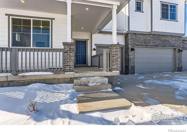 view of exterior entry with brick siding, a porch, and an attached garage