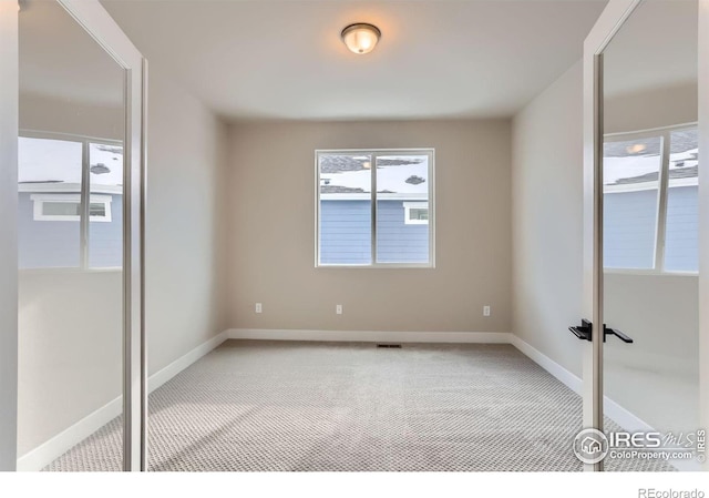 spare room featuring light carpet, visible vents, and baseboards