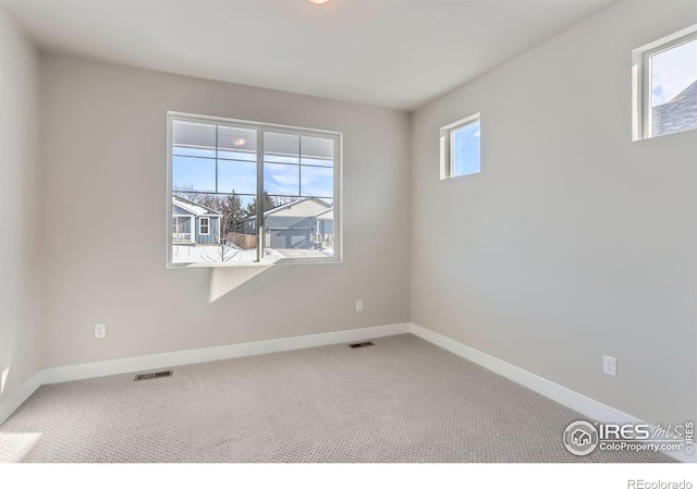 spare room featuring carpet flooring, baseboards, and visible vents