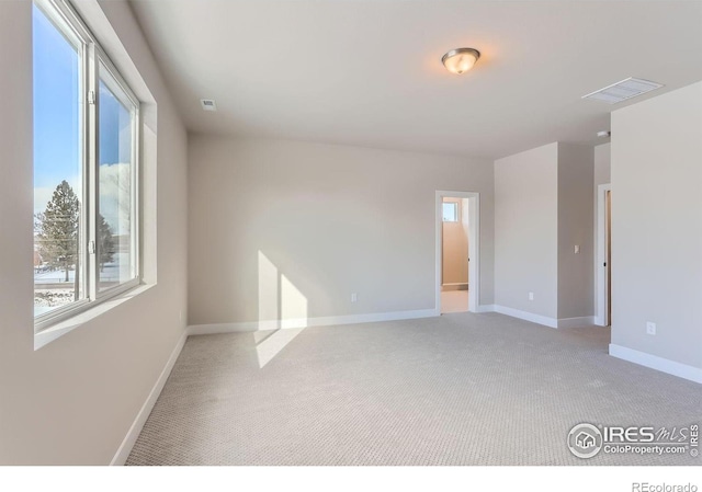 unfurnished room with visible vents, light colored carpet, and baseboards