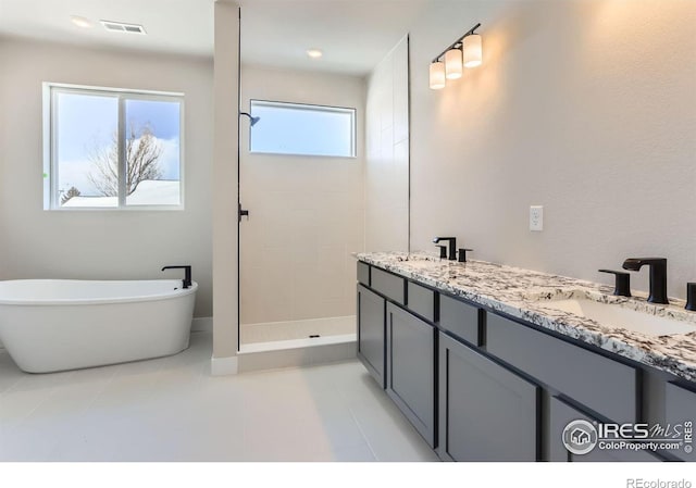 bathroom featuring a sink, visible vents, a freestanding bath, and a tile shower