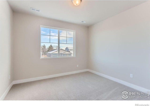 carpeted spare room featuring visible vents and baseboards