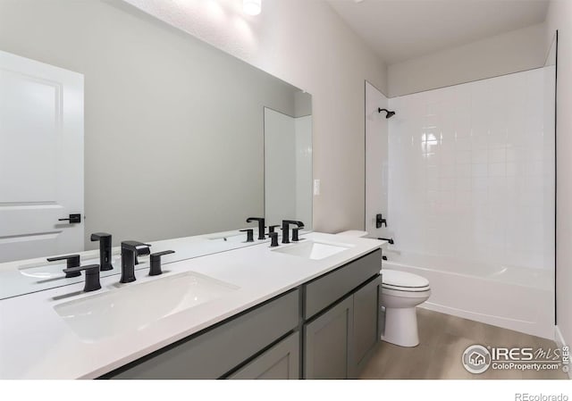 bathroom with wood finished floors, toilet, bathtub / shower combination, and a sink