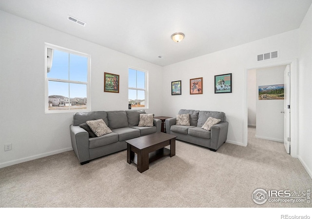 carpeted living area featuring baseboards and visible vents