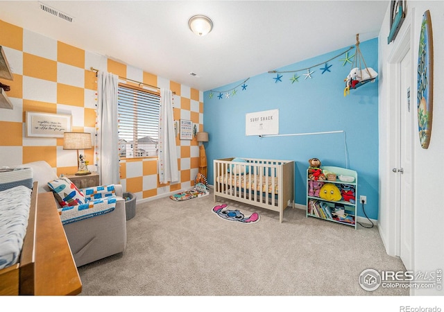 carpeted bedroom with visible vents, baseboards, a crib, and wallpapered walls