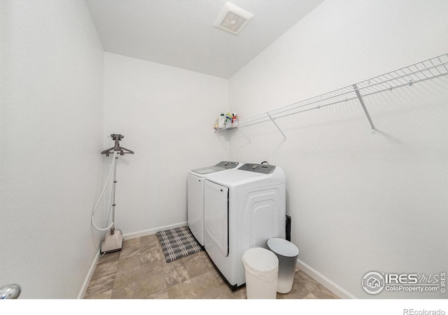 clothes washing area featuring visible vents, baseboards, laundry area, and washing machine and clothes dryer