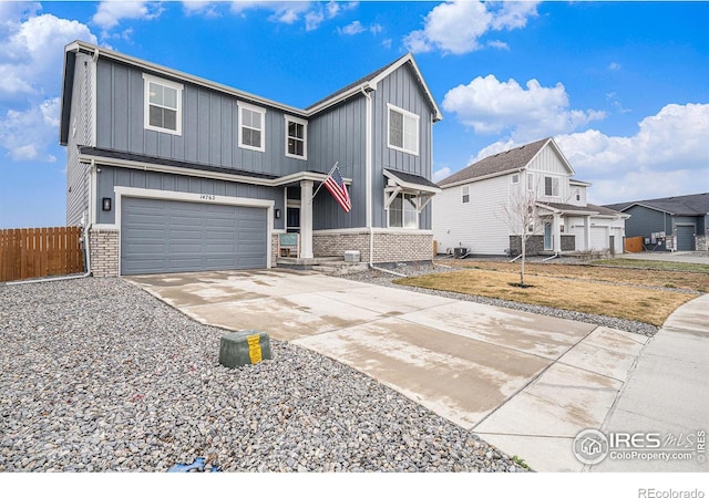 traditional-style home featuring driveway, fence, board and batten siding, an attached garage, and brick siding