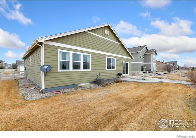 back of property featuring board and batten siding, fence, central AC unit, a yard, and a patio