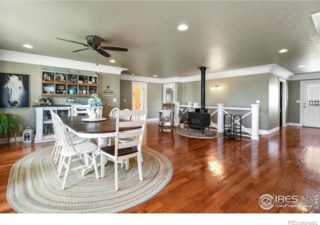 dining space featuring a wood stove, a textured ceiling, a ceiling fan, wood finished floors, and wine cooler