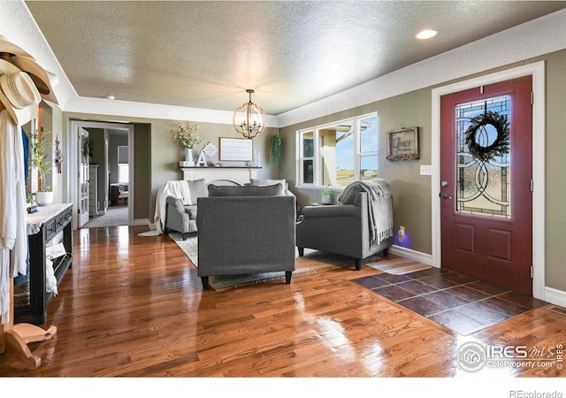 foyer entrance featuring a notable chandelier, dark wood-style flooring, and a textured ceiling